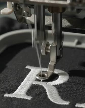 A logo stitched in thread, close on the letter