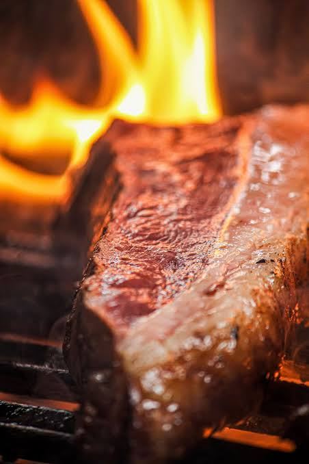 A steak hitting the grill, close enough to smell it