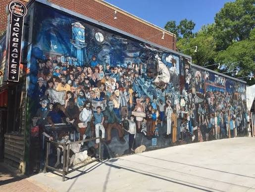 The NoDa community mural on North Davidson Street in Charlotte, a long blue wall crowded with hundreds of painted figures beside the Jack Beagle&rsquo;s sign