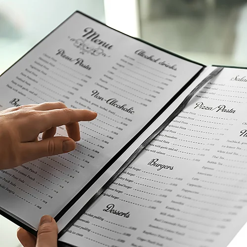 A laminated multi-page menu being read with a finger